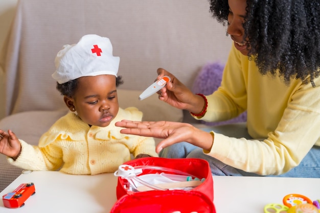 Une mère et sa fille africaines jouent aux médecins à la maison.