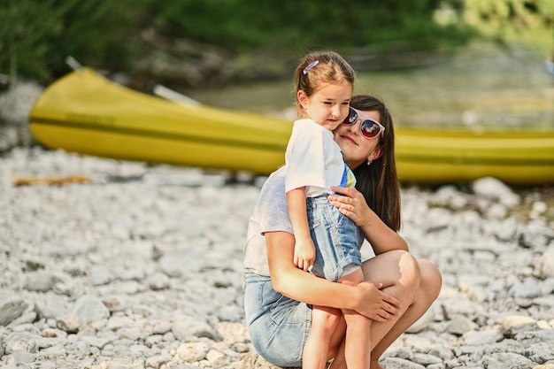 Mère avec sa fille contre canoë en rive rocheuse d'une rivière calme dans le parc national du Triglav en Slovénie