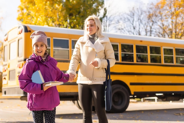 Mère et sa fille à côté du bus scolaire le matin.