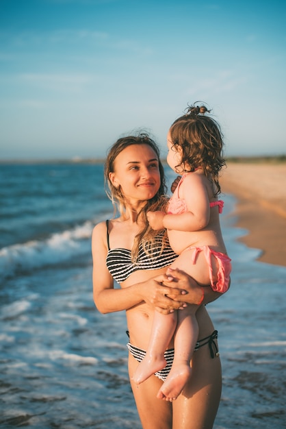 Mère avec sa fille dans ses bras dans le contexte de la mer d'Azov en Crimée cool