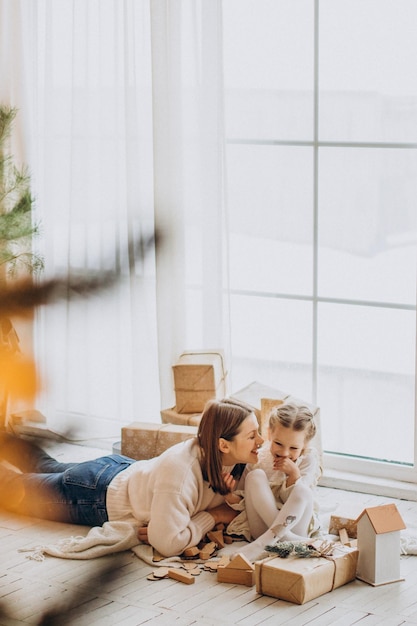 Mère avec sa fille emballant des cadeaux de Noël et s'amusant