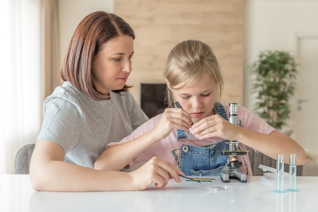 Une mère et sa fille font des expériences chimiques avec un microscope à la maison