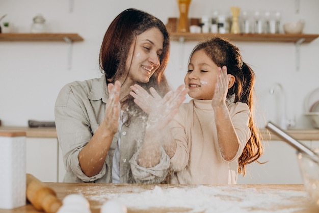 Mère avec sa fille jouant avec de la farine et de la cuisson à la cuisine