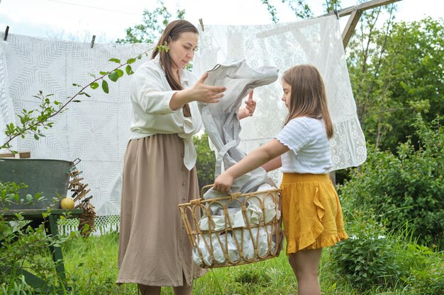 Photo une mère et sa fille joyeuses partagent un moment ludique en ventilant la lessive dans leur jardin luxuriant.