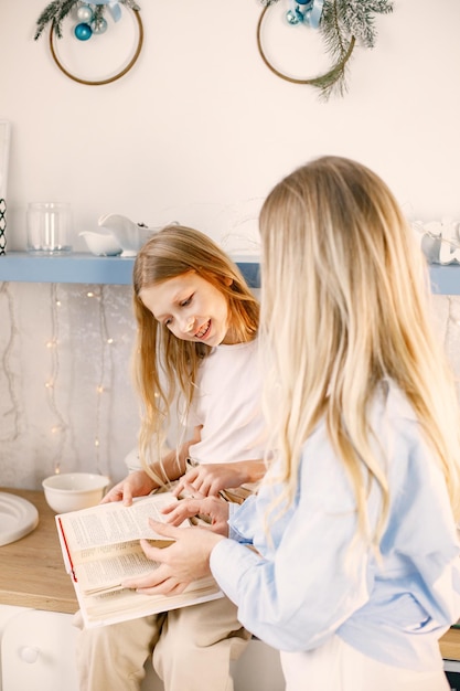 Mère et sa fille lisant un livre avec des recettes à la cuisine