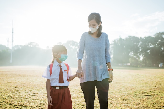 Mère et sa fille marchant ensemble et portant un masque facial