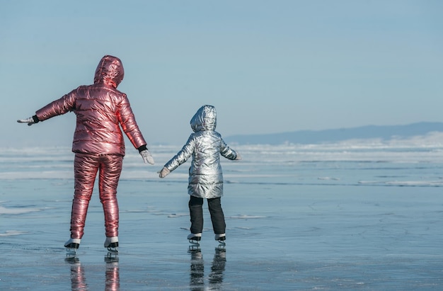 La mère avec sa fille patine sur la glace du paysage sibérien d'hiver du lac Baïkal