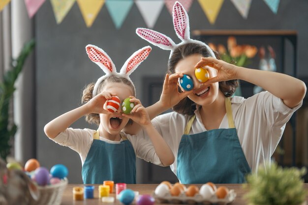 Mère et sa fille peignant des oeufs Mignonne petite fille enfant portant des oreilles de lapin