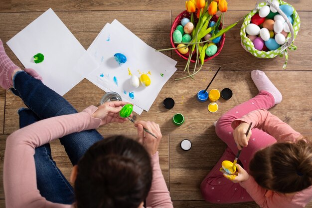 Une mère et sa fille peignant des œufs de Pâques à la maison