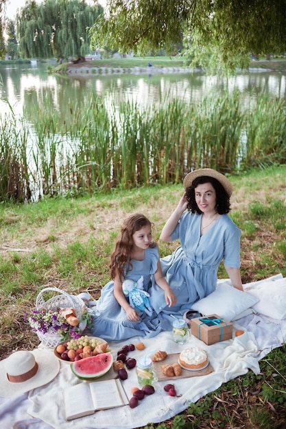 Une mère et sa fille en pique-nique dans un parc au bord d'une rivière