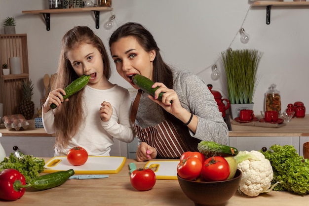 La mère et sa fille préparent une salade de légumes et s'amusent à la cuisine.