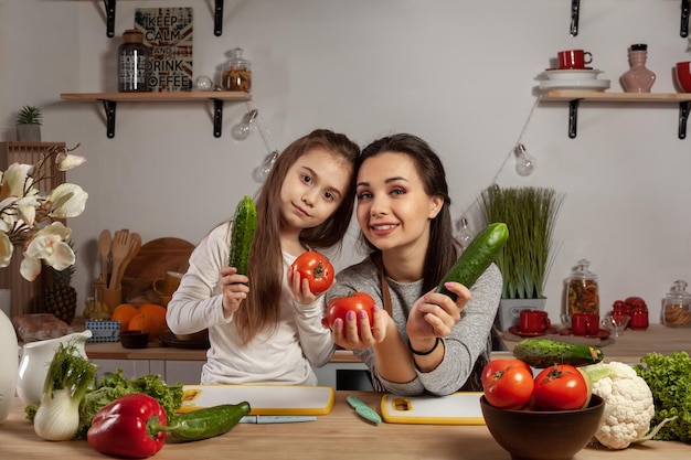 La mère et sa fille préparent une salade de légumes et s'amusent à la cuisine.