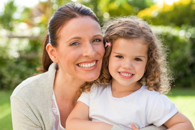 Mère avec sa fille en regardant la caméra dans le jardin