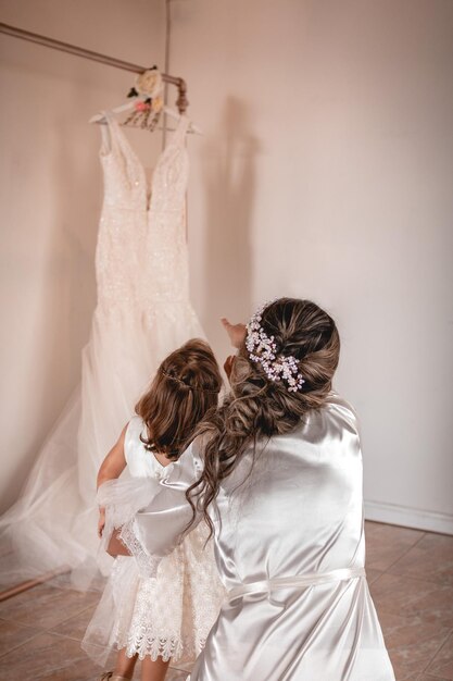 Photo mère avec sa fille regardant la robe de mariée le jour de son mariage