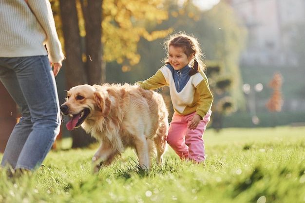 Mère avec sa fille se promène avec un chien Golden Retriever dans le parc