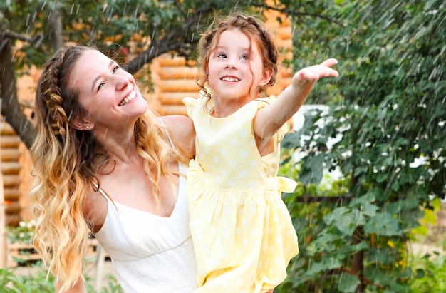 Photo une mère et sa fille souriantes dehors pendant la saison des pluies