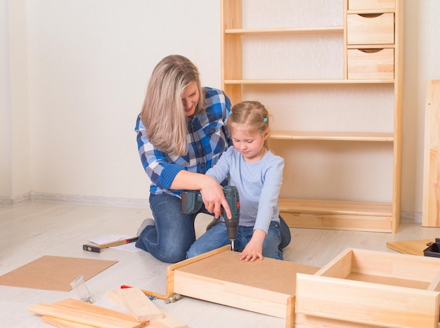 Mère et sa petite fille assemblant des meubles ensemble