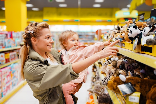 Mère avec sa petite fille en choisissant des jouets dans le magasin pour enfants.