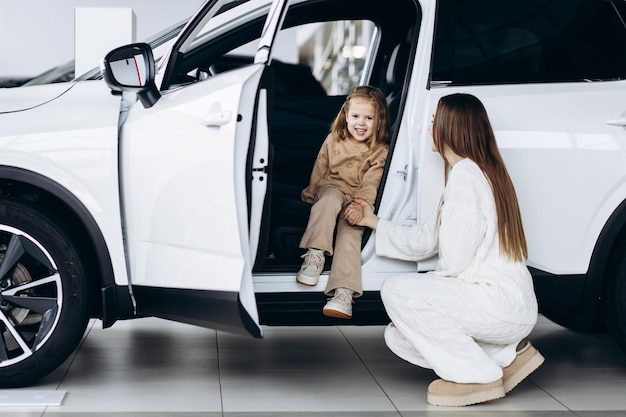 Photo mère avec sa petite fille choisissant une voiture dans une salle d'exposition de voitures