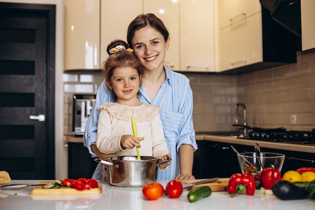 Mère avec sa petite fille cuisinant à la cuisine et s'amusant