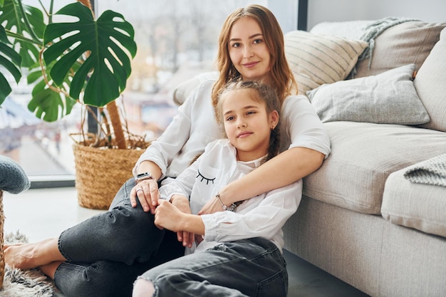 Mère avec sa petite fille est assise sur le sol dans la chambre domestique