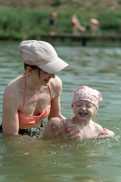 Mère avec sa petite fille nageant Vacances d'été avec enfants Fille de deux ans éclabousse dans l'eau et rit