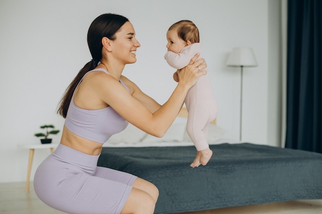 Mère avec sa petite fille pratique le yoga à la maison