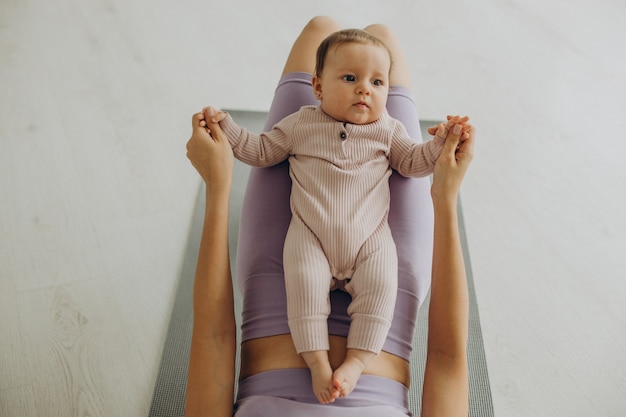 Mère avec sa petite fille pratique le yoga à la maison