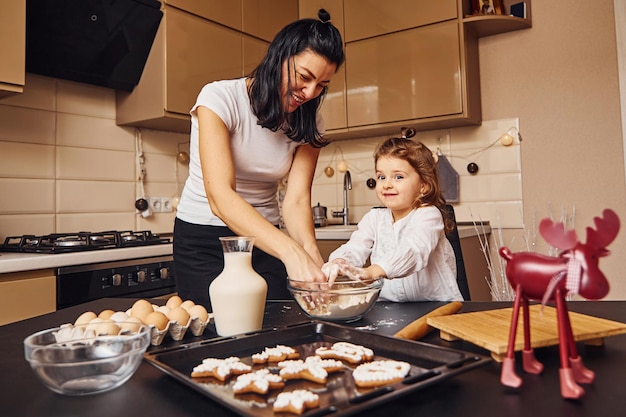 Mère avec sa petite fille prépare de la nourriture dans la cuisine et s'amuse.