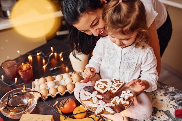 Mère avec sa petite fille prépare de la nourriture dans la cuisine et s'amuse.