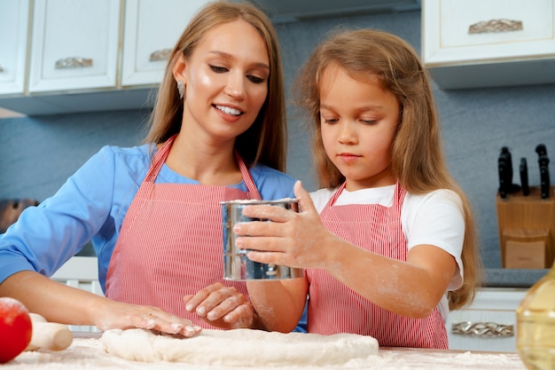 Mère et sa petite fille préparer la pâte dans la cuisine