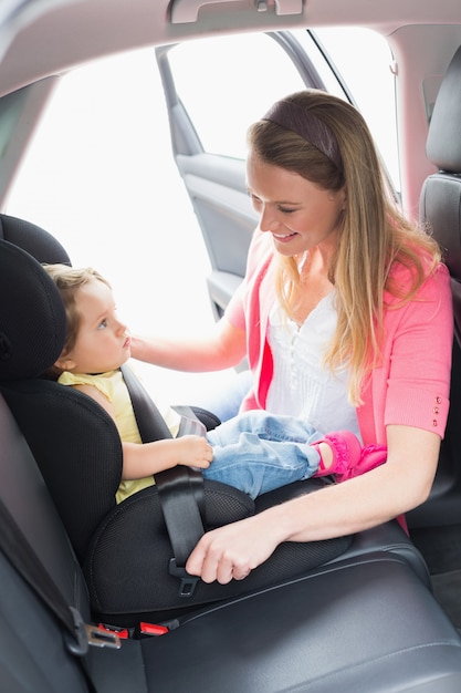 Mère sécurisant son bébé sur le siège auto