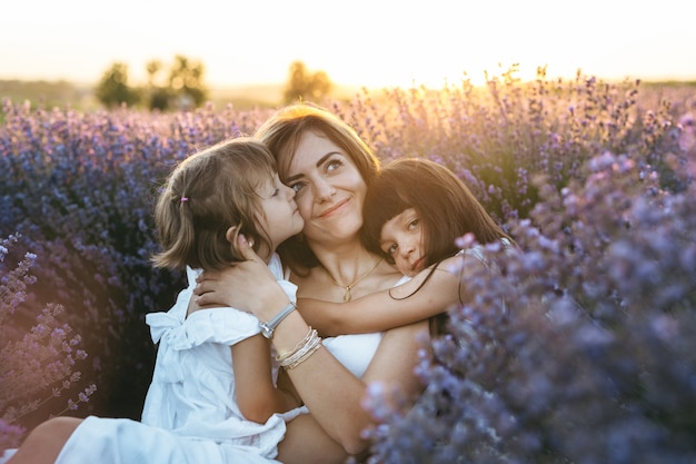 Une mère avec ses filles au coucher du soleil dans le champ de lavande au coucher du soleil. Concept de la Journée internationale de la femme