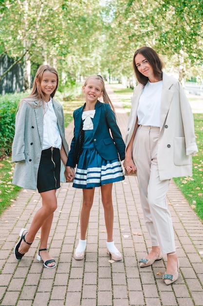 Mère et ses filles à l'école. Adorables petites filles très excitées à l'idée de retourner à l'école