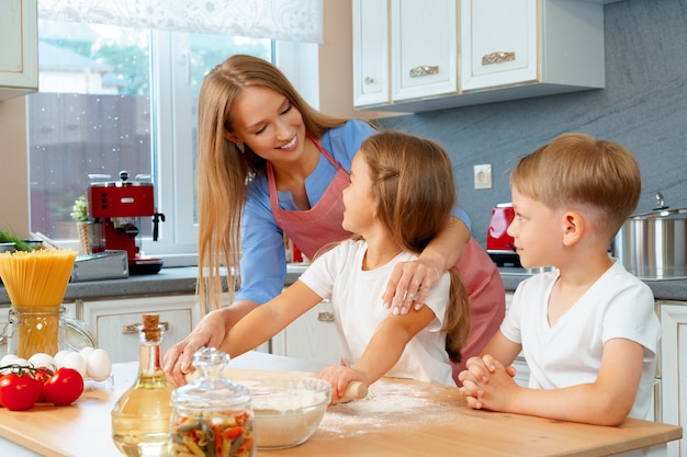 Mère et ses petits enfants, garçon et fille, l'aidant à préparer la pâte