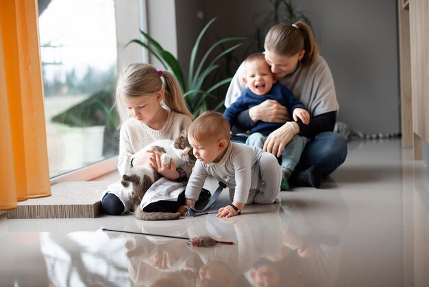 mère avec ses trois enfants jouant avec un chat par terre à la maison