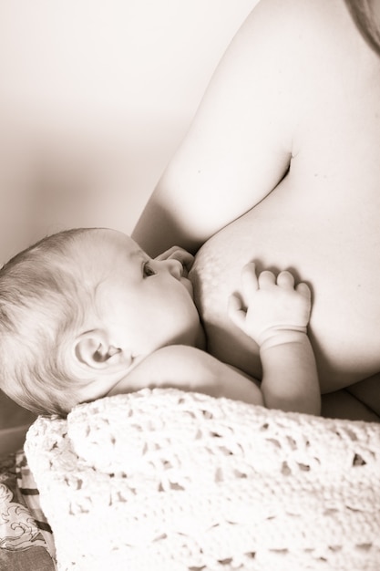 Photo mère avec son bébé allaité nouveau-né, assis sur un dessin à bascule