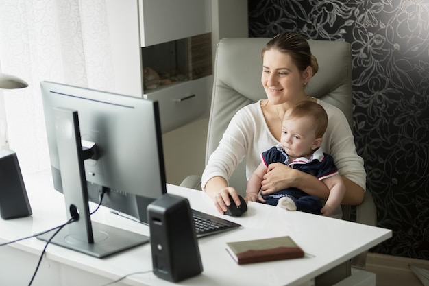 Mère Avec Son Bébé Au Bureau à L'aide D'un Ordinateur