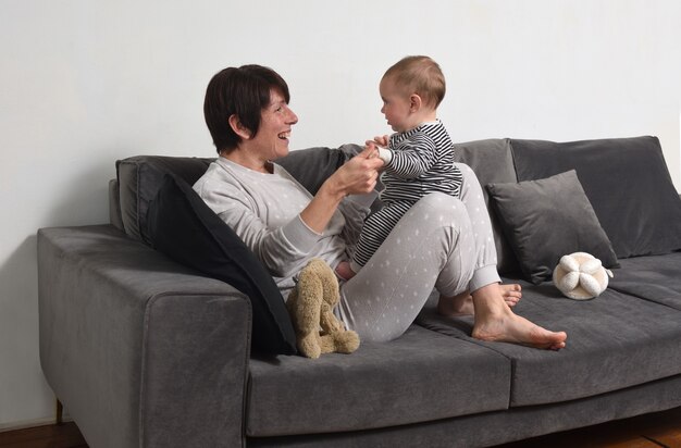 Mère avec son bébé jouant sur le canapé avec pyjama