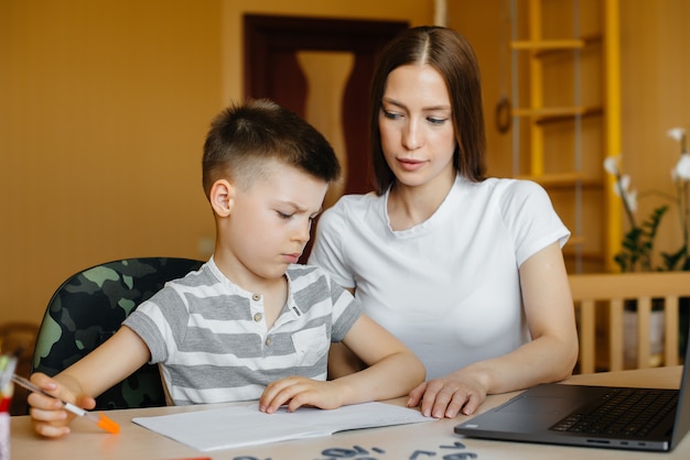 Une mère et son enfant suivent un enseignement à distance à la maison devant l'ordinateur. Restez chez vous, entraînez-vous.