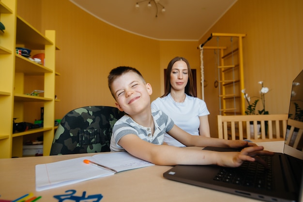 Une mère et son enfant suivent une formation à distance à la maison devant l'ordinateur