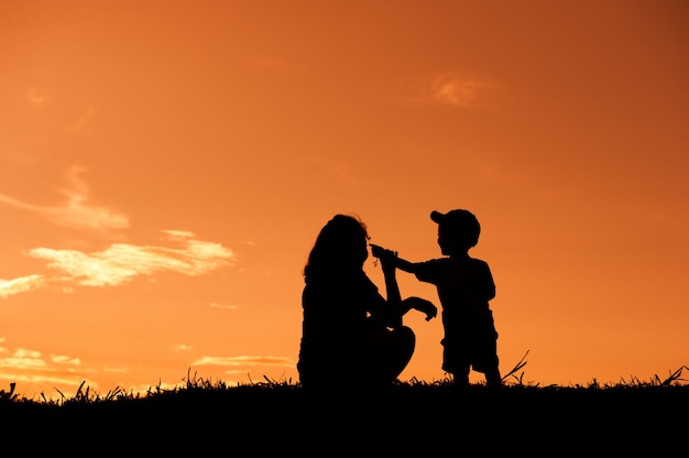 Une mère et son fils jouent à l&#39;extérieur au coucher du soleil