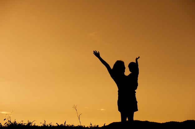 Une mère et son fils jouent à l&#39;extérieur au coucher du soleil