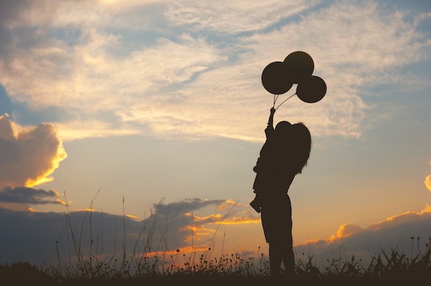 Une mère et son fils jouent en plein air au coucher du soleil silhouette