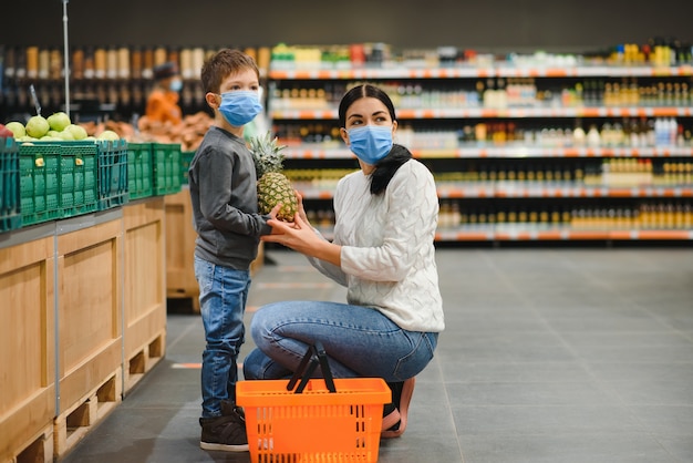 Une mère et son fils portant des masques protecteurs dans un supermarché pendant l'épidémie de coronavirus