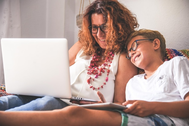 Une mère et son fils souriants utilisant des technologies à la maison