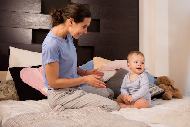 Photo mère avec son mignon petit fils jouant sur le lit