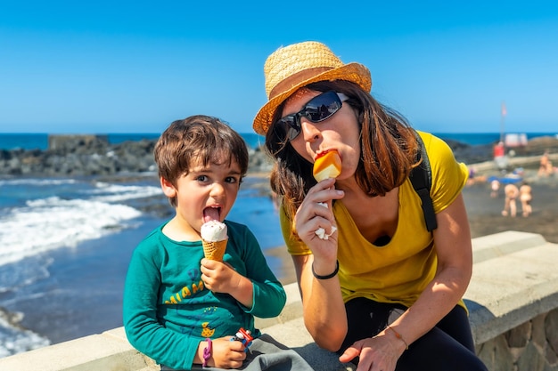 Une mère avec son petit fils apprécient les vacances d'été en mangeant de la crème glacée