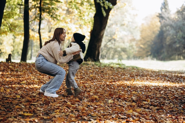 Mère avec son petit fils marchant dans le parc automnal