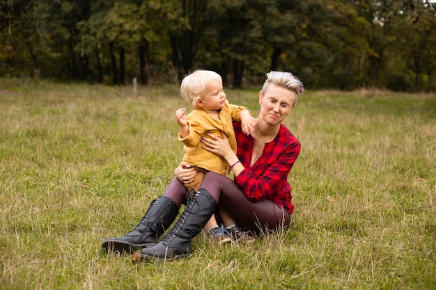 Mère avec son petit garçon jouant sur le pré sur l'herbe en automne ou en été